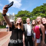 Class of 2024 grads pose for a selfie with President Troy Paino outside the Jepson Alumni Executive Center during the Senior Toast. Photo by Karen Pearlman.