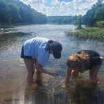 Morgan Hicok '25 (left) and Kate Green '25 collect specimens of freshwater snails in the Rappahanock River at Motts Run Reservoir. Photo courtesy of Kate Green.