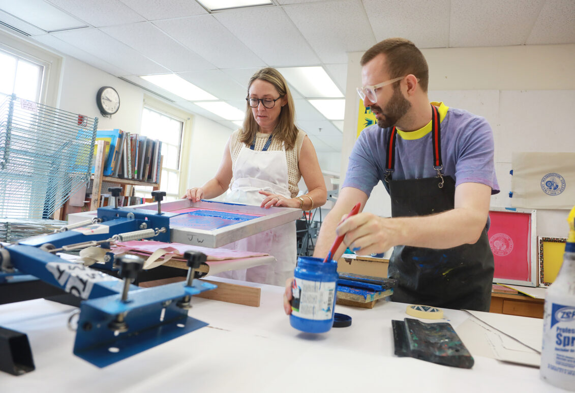 Courtney Quinn Hampton '00 silkscreens a Mary Washington College bag with Assistant Professor of Studio Art Coorain Devin as part of an Alumni College lecture. Photo by Karen Pearlman.