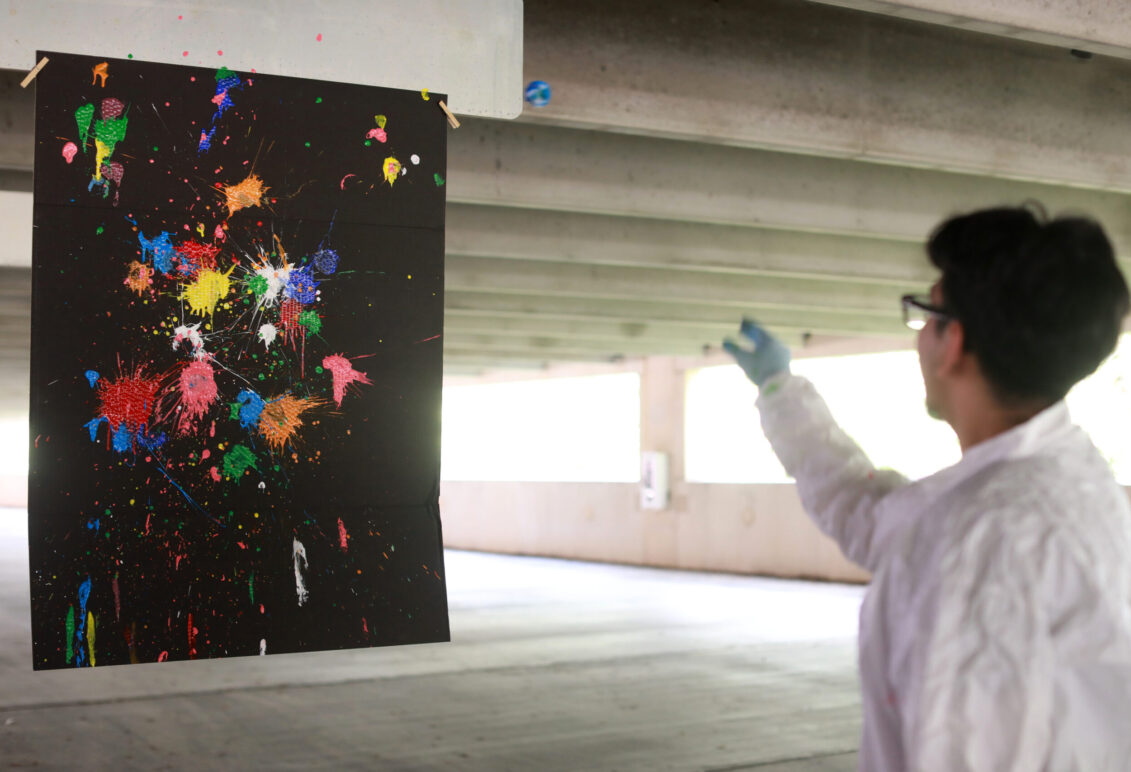 Alexander Rosas, a senior at Stafford High School, shows off his strategy of using heavily painted cotton balls on the right side of the canvas and reused cotton balls on the left side to demonstrate that the amount of energy put into an object correlates to its outcome. Alexander, who is involved with robotics and technology clubs in high school, said he was excited to connect with members of the physics community in Fredericksburg by participating in the PING program. Photo by K Pearlman Photography.