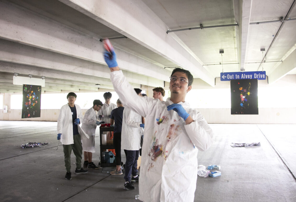 High schooler Maiwand Barakzai chucks a painted cotton ball at a canvas while his classmates look on. Photo by K Pearlman Photography.