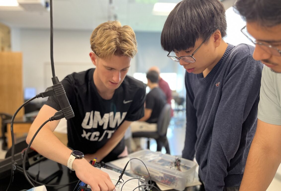 From left: CJ Hulleman '28, one of the PING program mentors, demonstrates to high schoolers Michael Young and Maiwand Barakzai how to construct a circuit that measures the effect of resonance, a physics concept that can be applied to engineering, biomedicine, and technology. Photo by Katie VanHouten '26.