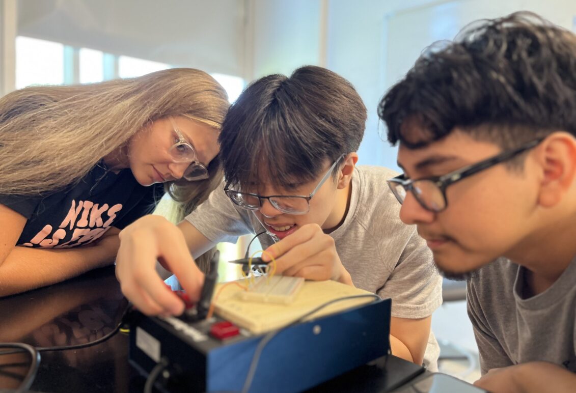 Hannah Steele '26, a UMW student mentor and Noyce Scholarship recipient, guides high schoolers Vincent Phan (left) and Alexander Rosas in creating a circuit. Photo by Katie VanHouten '26.