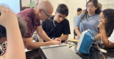 UMW Physics Chair and Professor Matt Fleenor demonstrates how to construct a circuit to high schooler Zubair Mohammadzai (center), while UMW student mentor Aliya Ather and volunteer mentor Emma Wallach (right) observe. Photo by Katie VanHouten '26.