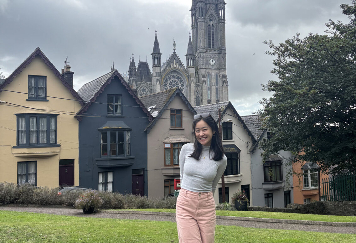 Mallory standing in front of colorful houses known as the "Deck of Cards," a popular tourist attraction in Cobh, Ireland.