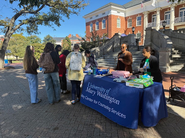 Talley Center staff Amira Niori (right), Jimmy Nguyen (left), and Debbie Huff (not pictured), along with Marissa Miller (center), director of UMW's Center for Prevention and Education, hand out cookies and sandwiches on Campus Walk during Talley Treats. Held on Thursdays throughout October, the initiative promotes well-being and connection at a point in the semester that can feel overwhelming to students. Local vendors, including several alumni, provide the treats and gift cards for raffles.